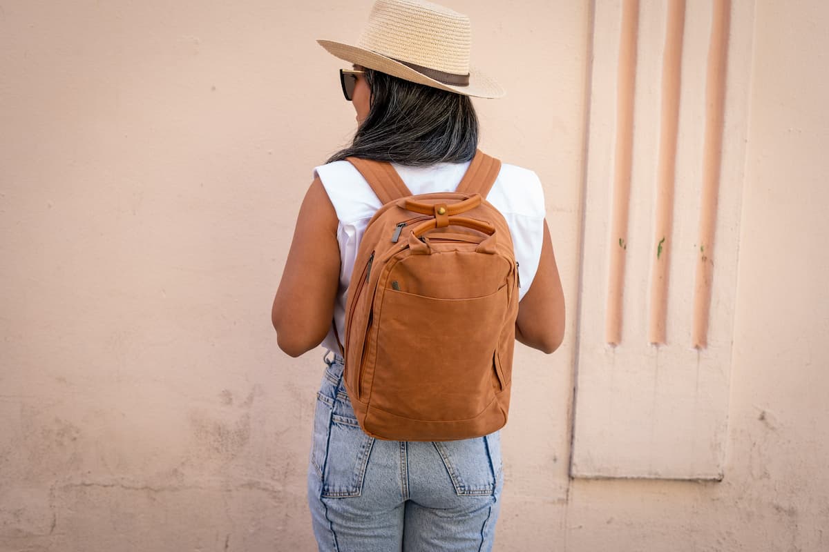 Pessoa de costas vestindo mochila Ecopack laranja.